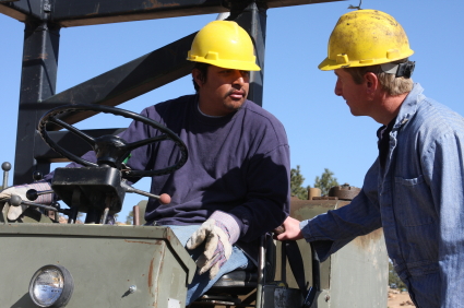 two construction workers wearing yellow hard hats talking to each other